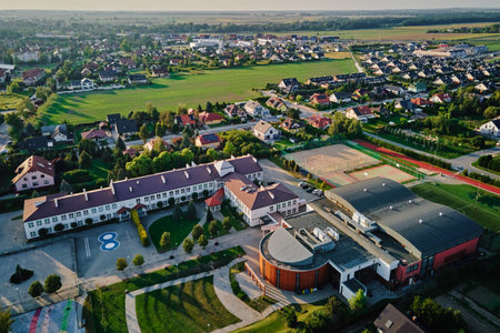 Aerial view of large school complex with classrooms, gymnasium, sports courts, surrounding suburban...