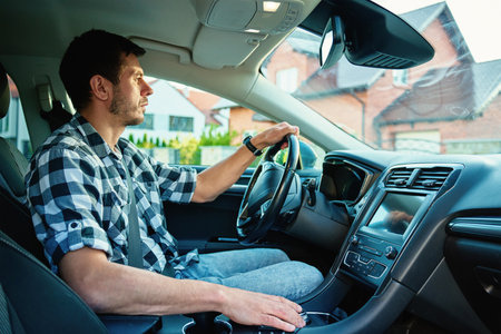 Man driving car and looking ahead with focus, sitting in modern vehicle interior. Concept of daily commute, safe driving and transportationの写真素材