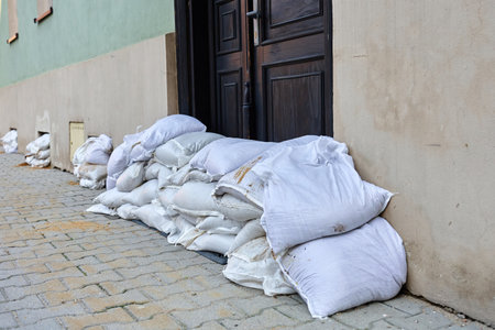 Sandbags stacked in front of door to protect building from flood water. Emergency defense measure against storm damage and natural disaster in urban residential areaの写真素材