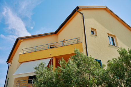 Modern house facade with windows, balcony and garden. Contemporary residential architecture under blue skyの写真素材