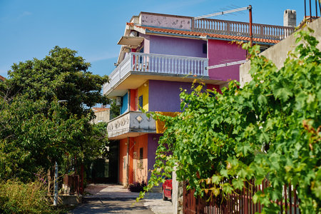Colorful apartment building with red, purple, yellow and blue walls and balconies surrounded by lush greenery and grapevines. Residential architecture in coastal townの写真素材