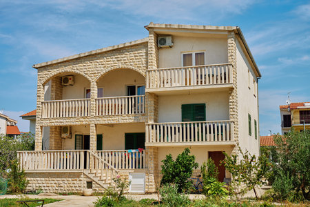 Traditional Mediterranean house with stone walls and green shutters against blue sky. Traditional residential architecture in coastal townの写真素材