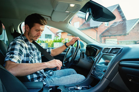 Man fastening seat belt inside modern car, preparing to drive. Concept of road safety and responsible drivingの写真素材