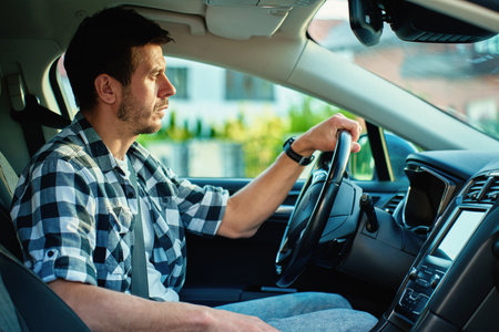 Man driving car and looking ahead with focus, sitting in modern vehicle interior. Concept of daily...