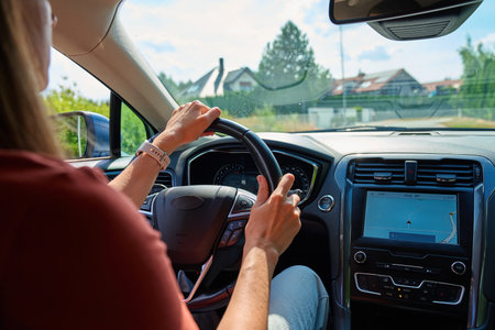 Woman driving modern car with GPS navigation on screen, hands on steering wheel. Concept of modern...