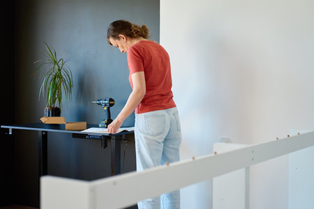 Woman reading instruction manual during furniture assembling. DIY home renovation and home organization after moving conceptの写真素材