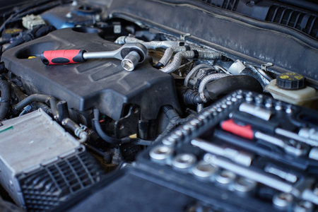 Close-up of wrench socket tool lying on car engine during maintenance work. Vehicle repair concept