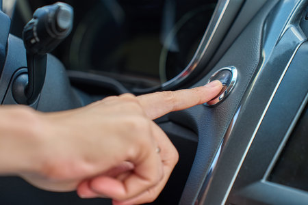 Close-up of hand pressing start button to turn on car engine. Keyless ignition system in modern car