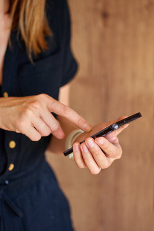 Close-up of woman using modern smartphone at home Female hands tapping touchscreen while holding mobile phone. Concept of technology, mobile communication and everyday digital lifeの写真素材
