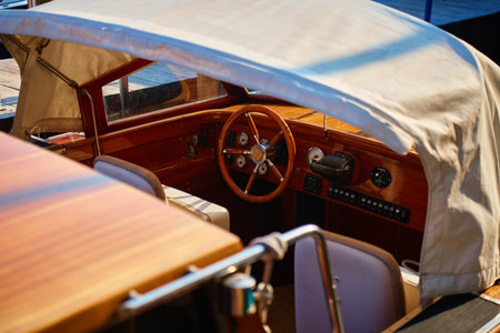 Close up of wooden steering wheel and dashboard inside motorboat cabin. Concept of boating, water transport and luxury travelの写真素材