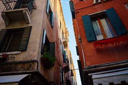 Narrow street between old Venetian buildings with open windows and balconies. Concept of travel and Italian architectureの写真素材