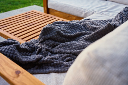 Wooden outdoor sofa and table with soft cushions and gray blanket on patio terrace. Concept of relaxation, comfort and modern outdoor lifestyleの写真素材