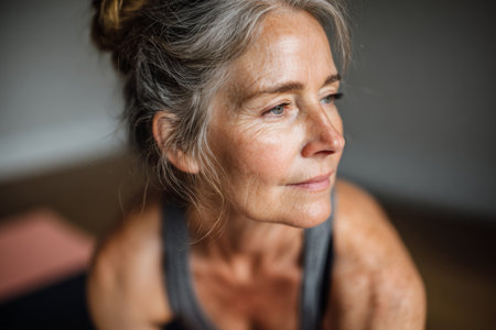 Close-up of an older woman performing an indoor workout exercises at home. Concept of fitness, active aging and wellnessの素材