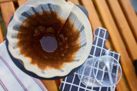 Used coffee filter with grounds residue in dripper on glass carafe