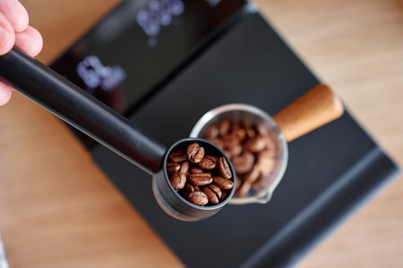 Roasted coffee beans measured with a scoop and glass container on a digital scale before grinding and brewing coffee.