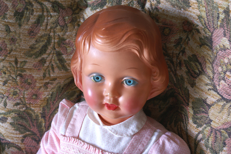 Old blue eyed doll sitting in chair.               の写真素材