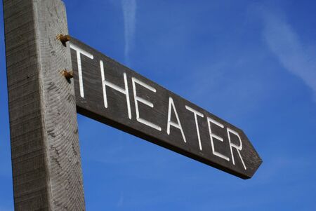 Wooden theater sign in shape of an arrow against a blue sky.           の写真素材