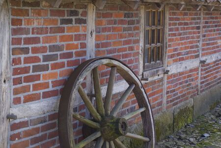 Part of an old wooden wheel in front of an ancient farm.の写真素材