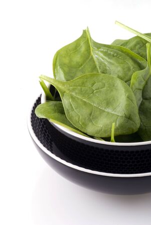 Bowl with fresh raw spinach on a white background.の写真素材