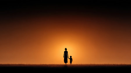 A serene silhouette of a mother and child walking hand in hand at sunset, showcasing the bond between them as the warm orange glow sets the scene.の素材