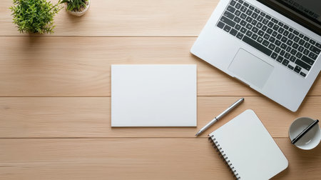 A minimalist flat-lay of a computer and writing materials, including a journal and pens, all neatly organized on a wooden desk.の素材