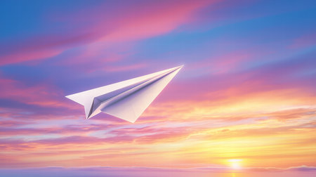 A paper airplane taking off into the sky against a colorful sunset, symbolizing aspirationsの素材