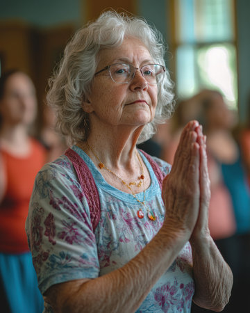 A senior woman practicing yoga with a group in a community centerの素材