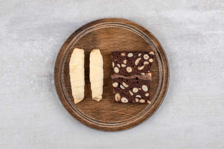 Wooden plate of traditional sweet mutaki and cocoa biscuits on stone background. High quality photoの写真素材