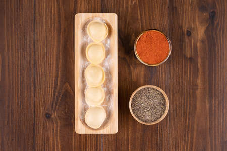 Wooden plate full of homemade pelmeni dumplings on wooden surface. High quality photoの写真素材