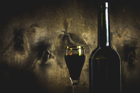 Red wine bottle and glass of wine on the dark wooden backgroundの写真素材