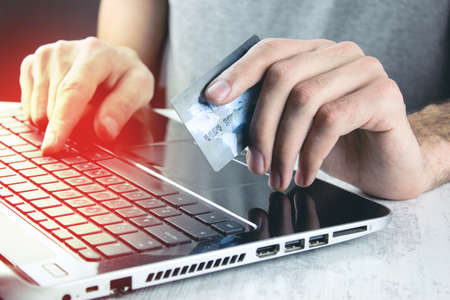 Hands using computer and holding credit card
