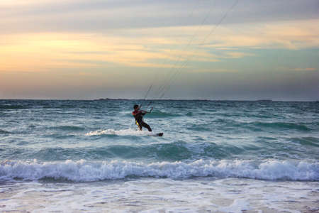 Young surfer rides the wave during sunsetの写真素材