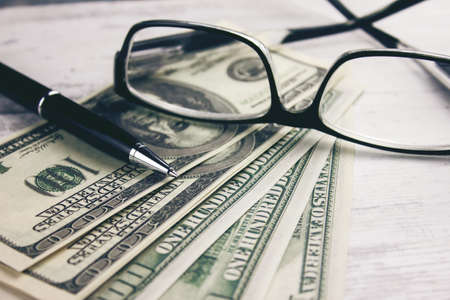 money with glasses and pen on the table