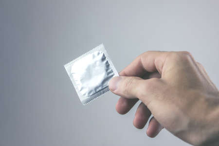 Closeup image of a young man with a condom
