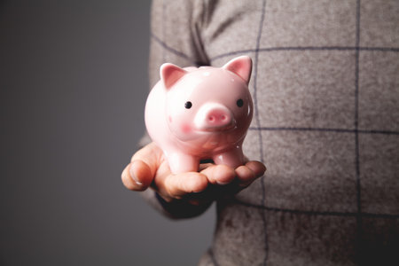Human hand protecting a piggy bank