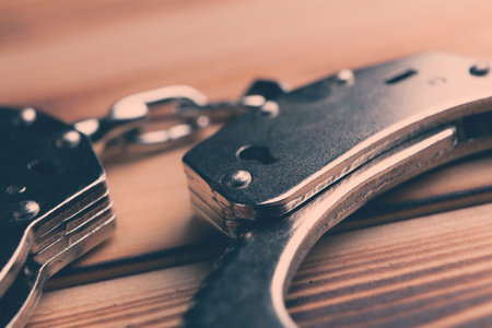 Isolated handcuffs, banner and copy space on a wooden background.
