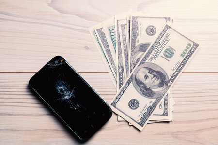 Modern broken mobile phone and dollarsの写真素材