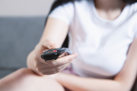 the girl watches TV and holds a remote control in her hands
