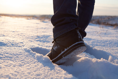 men's feet in boots in the snow walking in winterの写真素材