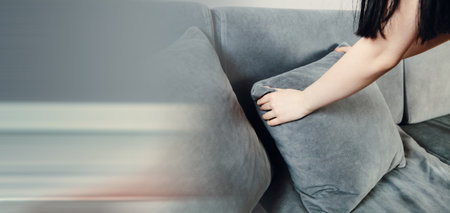 Woman straightens pillows on the sofaの写真素材