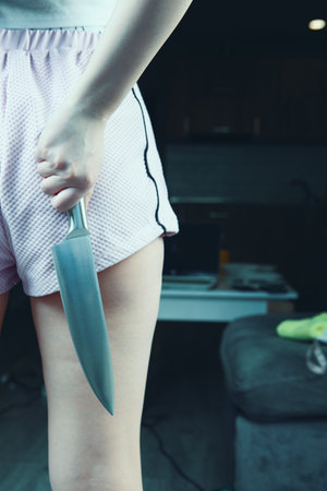 girl holding a kitchen knife to protect herselfの写真素材