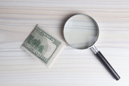 Hundred dollar bill and magnifying glass
