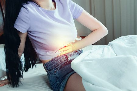 girl lying in bed suffering from stomach pain