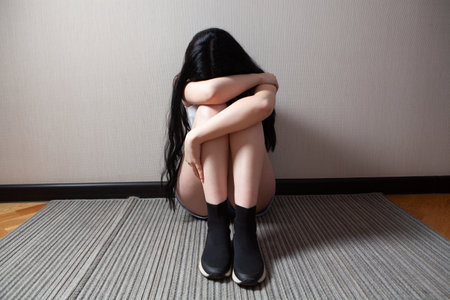 Battered young woman sitting near wallの写真素材