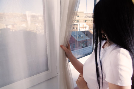 the girl looks out the window to the streetの写真素材