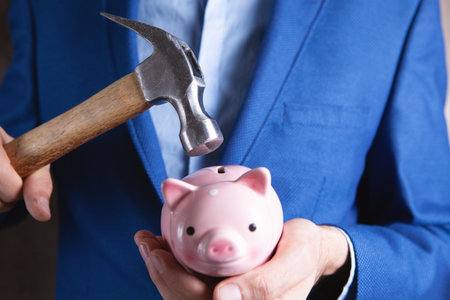 A sad pink piggy bank is about to be hit by a hammer in old vintage tone Financial problemの写真素材