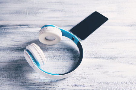 white headphones with phone listening to audio book or musicの写真素材