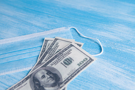Medical face mask and dollar money, world coronavirus epidemic and economic losses conceptの写真素材
