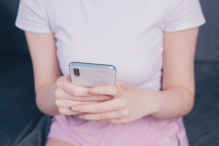 a young girl holding a phone in her handsの写真素材
