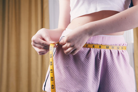 Woman measuring her waist with a measuring tape.